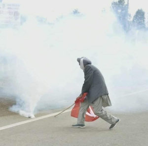 Dharampal Seel, a senior Kisan Sabha leader from Punjab, uses his Red Flag to push a tear gas canister, 27 November 2020.